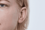 Audífono Oticon More, modelo miniRITE R, color Gris claro, vista frontal en ángulo de 45°, primer plano de la oreja, Audífonos Auzen mujer con servicio ilimitado