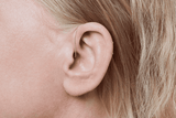 Audífono Oticon More, modelo miniRITE R, color Gris claro, foto tomada en ángulo de 90°, primer plano de la oreja, Mujer Audífonos con servicio ilimitado Auzen
